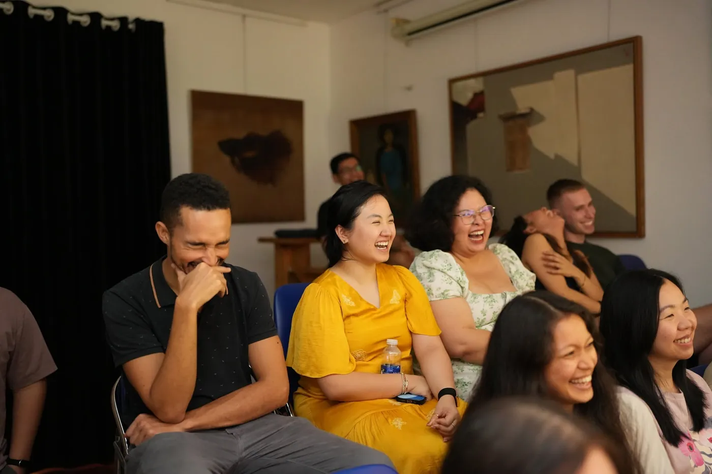Học viên kịch ứng tác ngồi cạnh nhau thả lỏng và bật cười tự nhiên trong lớp học