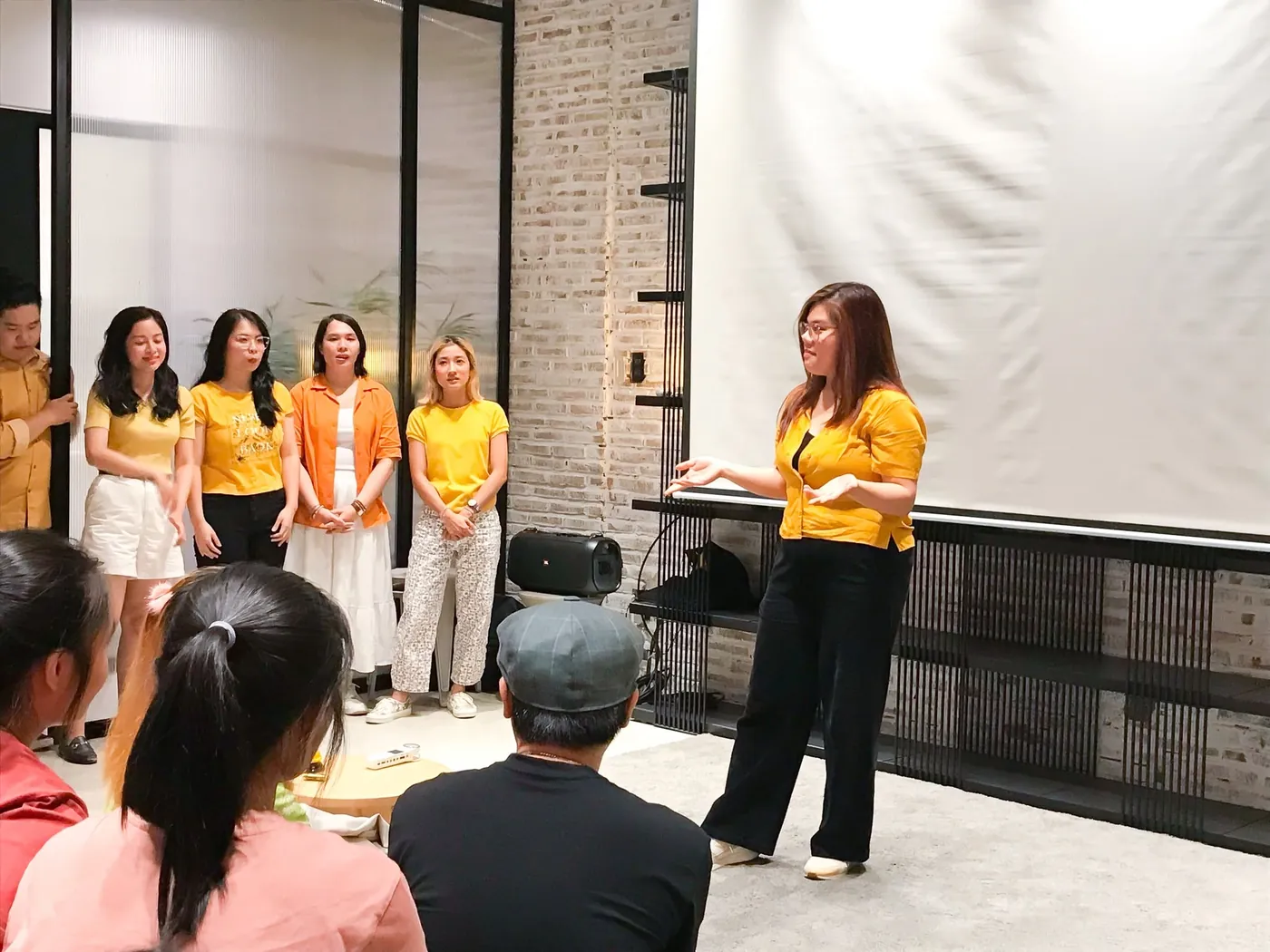 Vân Possible áo vàng mỉm cười mở tay khích lệ học viên trong phòng tập kịch ứng tác