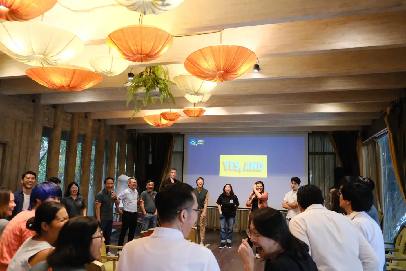 Nhóm học viên cười rạng rỡ trong buổi đào tạo ứng tác trước màn chiếu Yes, and