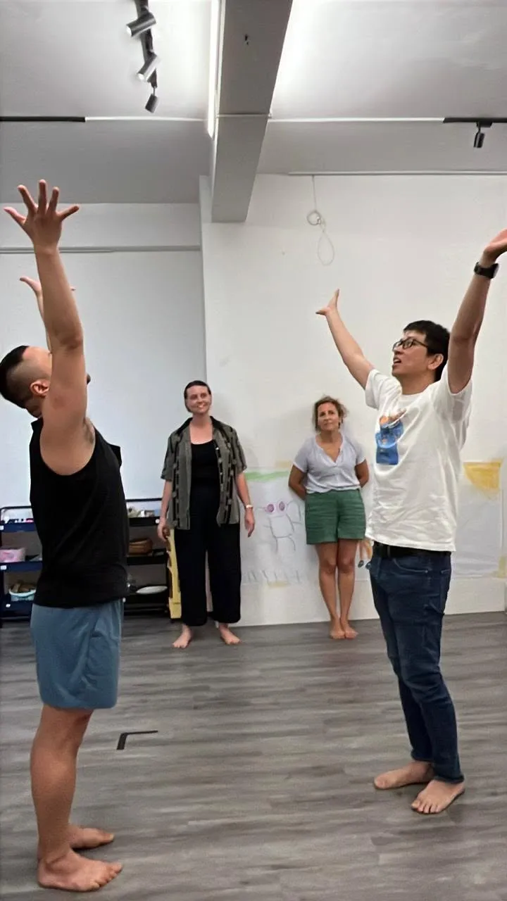 Học viên lớp Improv Movement giơ hai tay lên cao trong phòng tập