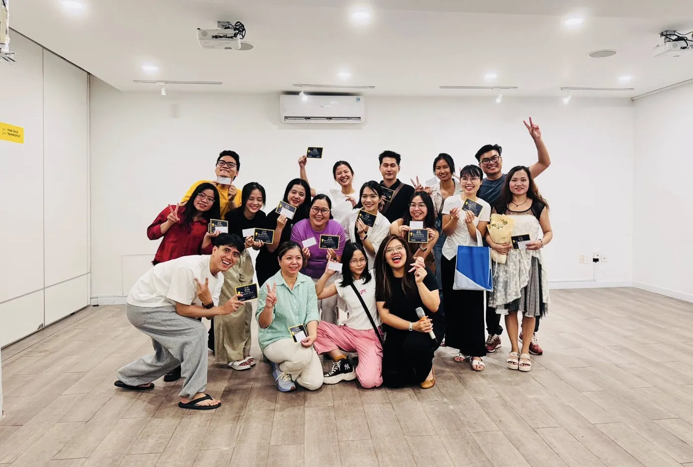 Học viên lớp kịch ứng tác cầm thẻ chứng nhận chụp ảnh nhóm trong phòng học