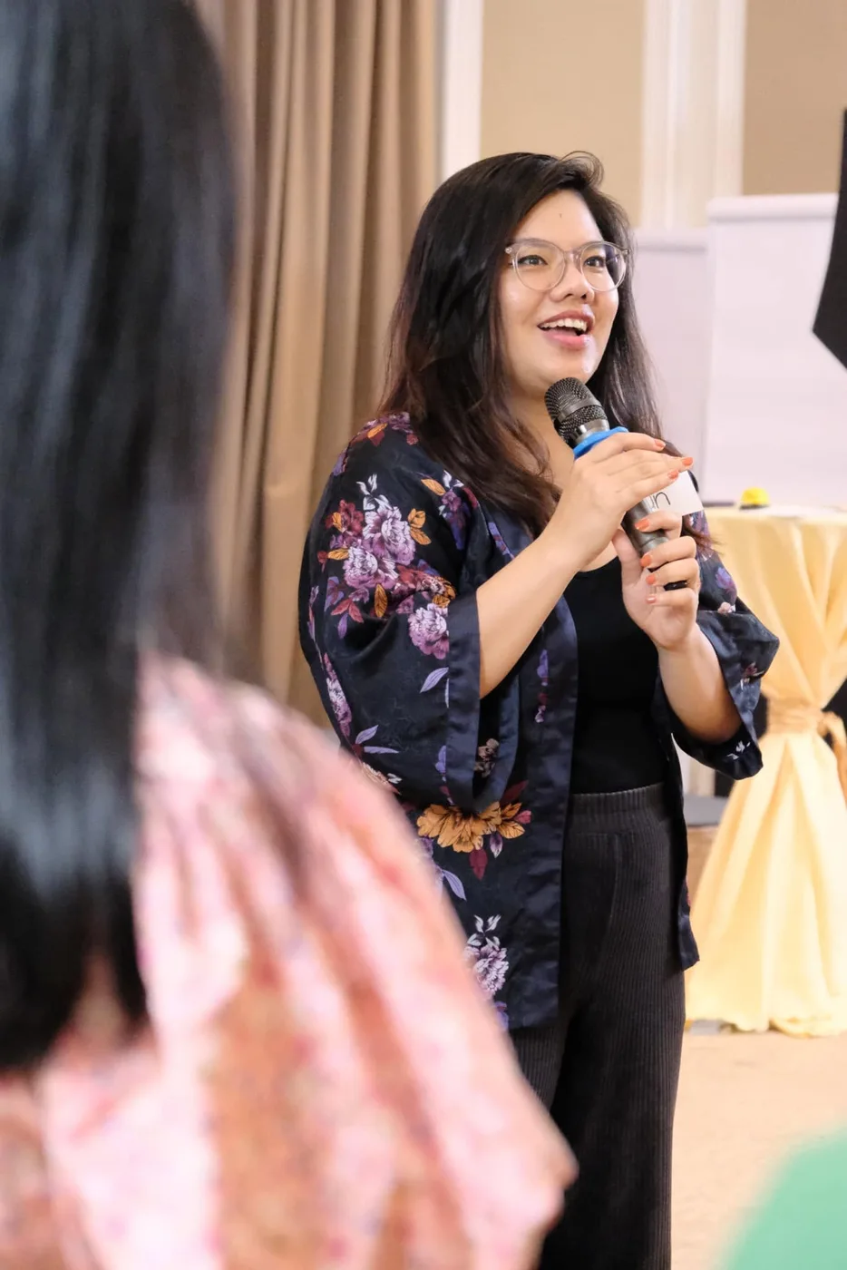 Vân Possible tươi cười cầm micro dẫn chương trình trong hội trường