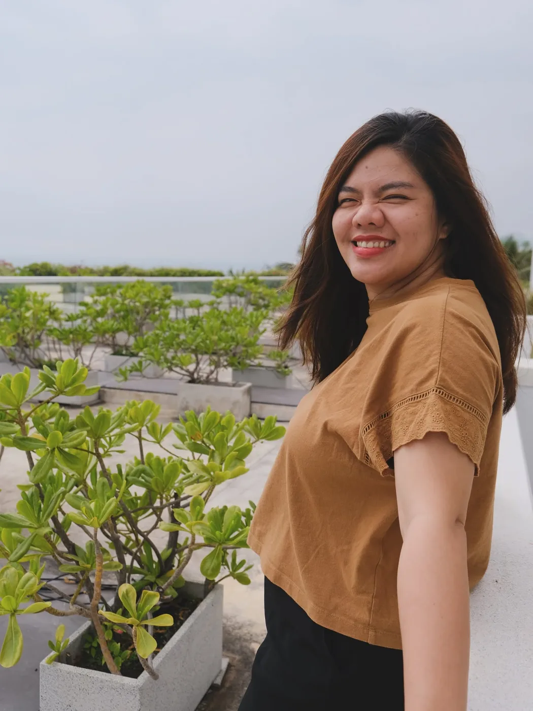 Vân Possible, founder Saigon Improv House, cười tươi bên những chậu cây trên sân thượng