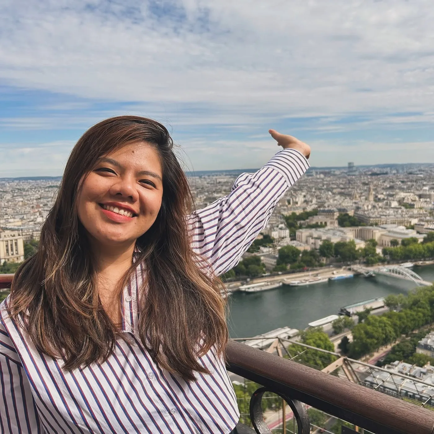 Vân Possible giơ tay tạo dáng trên cao với toàn cảnh Paris phía sau